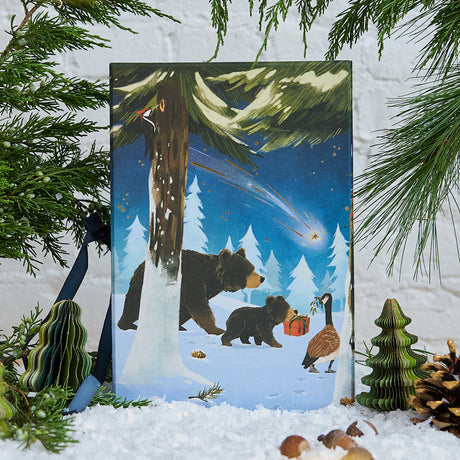 Craftspring’s handmade Woodland Minis Advent Calendar — back side featuring an illustration of woodland animals with a present and a shooting star, displayed with evergreens and snow for a magical Christmas scene, ethically crafted by artisans using sustainable wool.