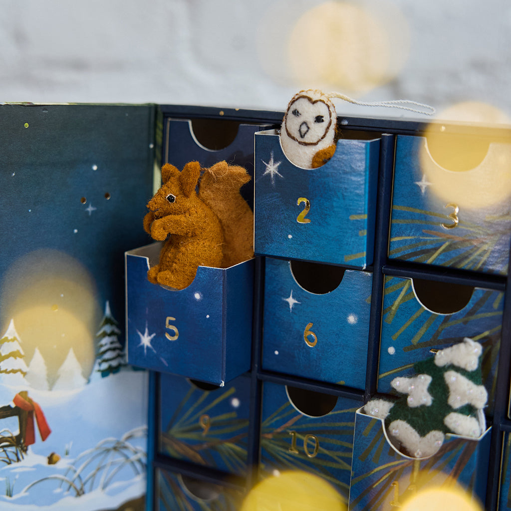 Craftspring’s handmade Woodland Minis Advent Calendar — close-up of three open drawers with mini ornaments of an owl, a snowy tree, and a squirrel peeking out, highlighting the magical woodland Christmas details, ethically crafted by artisans using sustainable wool.