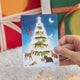 Craftspring’s Woodland Tree Greeting Card — held in hand in front of presents, featuring woodland animals around a glowing winter Christmas tree, ethically printed in the USA on natural textured paper, perfect for sharing holiday cheer and gifting.