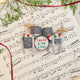 Craftspring’s Christmas Drum Set Ornament styled on sheet music with fresh evergreens — handmade felt holiday decor with embroidered “Santa and the Elves” band name and festive garland, ethically crafted by artisans using sustainable wool.