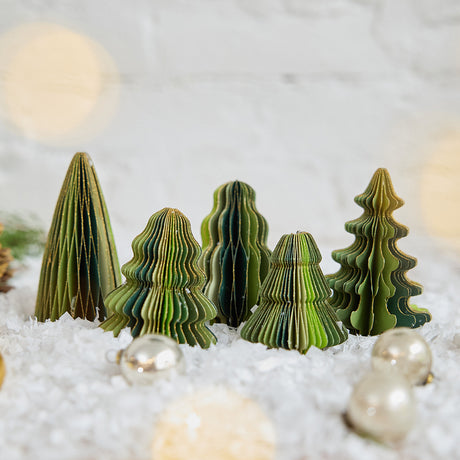 Craftspring’s Green Honeycomb Paper Mini Trees — Set of 5, displayed on snow with Christmas bobbles, showcasing their shades of green, gold edges, and unique shapes — handmade by artisans from recycled cotton waste for a festive holiday scene, perfect for gifting.