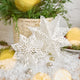 Craftspring’s Paper Snowflakes Christmas Ornaments — Set of 2, large white snowflakes with intricate cutout patterns, one slightly larger than the other — displayed on snow in front of a basket of evergreens, creating a festive holiday scene, ethically handmade by artisans from recycled cotton waste.