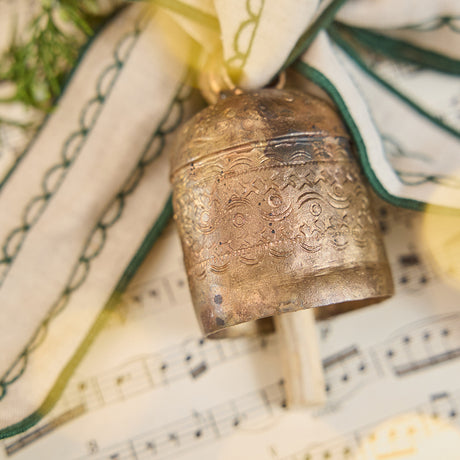 Close-up of Craftspring’s Embossed Bell with Green Ribbon showing the detailed embossed pattern on the bell and fine green embroidery on the linen ribbon — timeless holiday craftsmanship, ethically made by artisans.