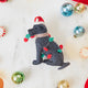 Craftspring’s Black Lab in Christmas Lights Ornament — felt dog wrapped in Christmas lights and wearing a Santa hat — styled among holiday baubles and peppermints, evoking festive warmth, playful holiday charm, and heirloom-quality gifting, ethically crafted by artisans using sustainable wool.