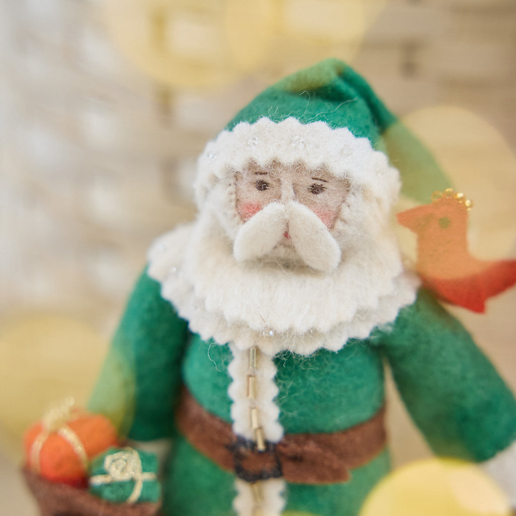 Craftspring’s Emerald Santa Mini Tree Topper — felt Santa in a green cloak with beaded details — close-up showing his sweet face and bird on his shoulder, highlighting whimsical vintage-style details, cozy holiday charm, and heirloom-quality Christmas gifting, ethically crafted by artisans using sustainable wool.