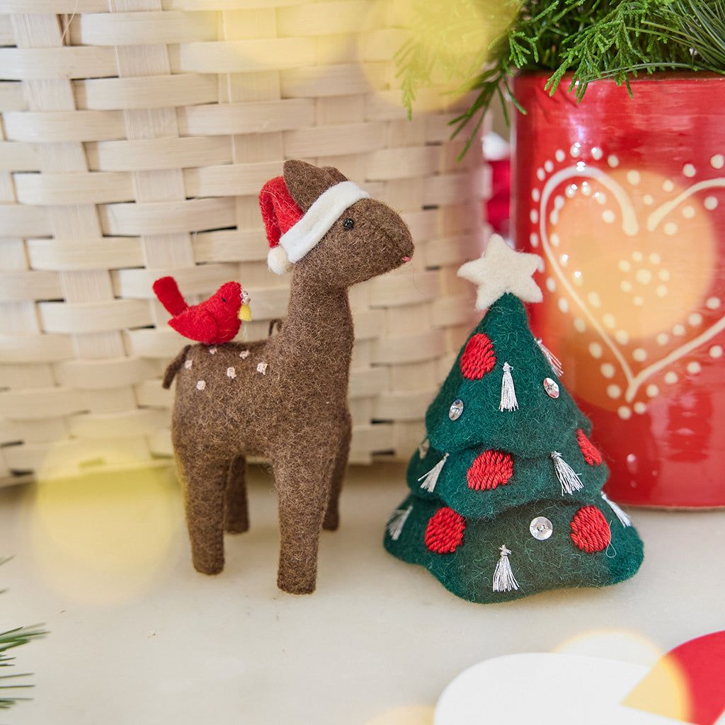 Craftspring’s Santa Deer with Bird Friend Ornament and Tinsel Tree — felt deer with a bird friend and felt tree with silver tinsel tassels, embroidered baubles, beaded ornaments, and a star on top — displayed together in front of a basket, evoking whimsical holiday charm, festive warmth, and heirloom-quality Christmas gifting, ethically crafted by artisans using sustainable wool.