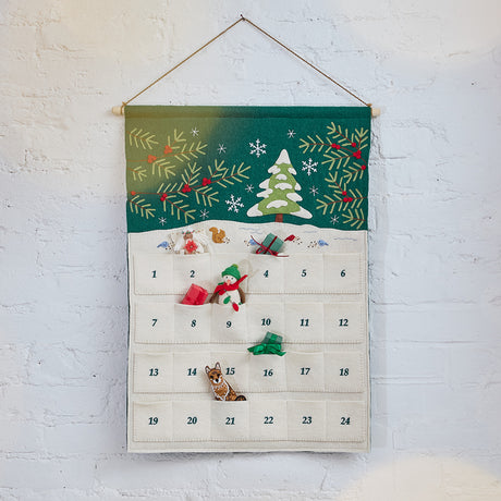 Craftspring’s Woodland Advent Calendar displayed with ornaments and mini presents tucked into its pockets — a snowy woodland scene with embroidered, appliqué, and beaded details brings festive holiday magic, ethically crafted by artisans using sustainable wool.