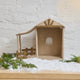 Craftspring’s Nativity Barn displayed on snow with fresh evergreens — handmade felt holiday decor designed to house the Holy Night Nativity Scene, ethically crafted by artisans using sustainable wool.