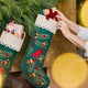 Craftspring’s handmade felt Woodland Stocking ornament — featuring intricate applique and embroidered details, including a cardinal sitting on a pine branch, displayed hanging on a fireplace mantle with evergreens and stuffed with presents for a festive holiday scene, perfect for Christmas decorating or gifting, ethically crafted by artisans using sustainable wool.