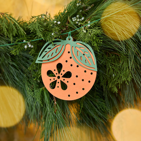Close-up of Craftspring’s Paper Clementine Garland — showing the intricate handmade paper details of a clementine with leaves, displayed on an evergreen garland for warm Christmas and holiday decor, ethically handmade by artisans from recycled cotton waste.