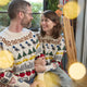 Craftspring’s NYC Holiday 100% Alpaca Sweater — ultra-soft crewneck made of sustainably harvested baby alpaca wool with intricate jacquard motifs of NYC icons like bagels, taxi cabs, and pigeons — ethically crafted by artisans in Peru. A couple wears the heirloom-quality sweaters in a festive holiday setting, perfect for Christmas warmth and gifting.