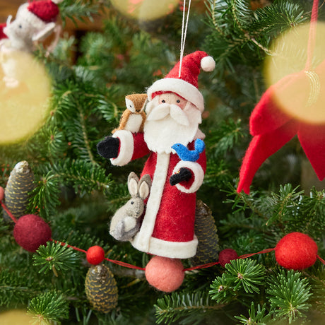Craftspring’s Santa with Woodland Animals ornament — featuring Santa with a bunny, bluebird, and owl perched on his arms holding beaded birdseed, displayed on a Christmas tree for a festive woodland holiday scene, ethically crafted by artisans using sustainable wool.