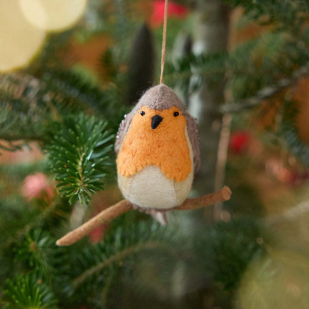 Craftspring’s European Robin ornament — featuring delicate beaded and embroidered details, displayed on a Christmas tree for a festive woodland holiday scene, ethically crafted by artisans using sustainable wool.
