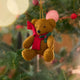 Craftspring’s Holiday Teddy Bear Ornament displayed on a Christmas tree — felt vintage-style teddy bear wearing a red scarf with holly, adding festive warmth and whimsical holiday charm — heirloom-quality Christmas decor, ethically crafted by artisans using sustainable wool.