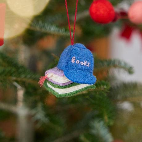 Craftspring’s Books Are Magic Hat with Books ornament — featuring a whimsical hat stacked with books, displayed on a Christmas tree for a festive holiday scene, ethically crafted by artisans using sustainable wool.