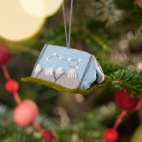 Craftspring’s Home Under the Stars Tent Ornament displayed on a Christmas tree — felt ornament with applique and embroidered mountains, the Big Dipper on the side, and a mini felt mattress inside, adding whimsical and festive holiday charm, ethically crafted by artisans using sustainable wool.