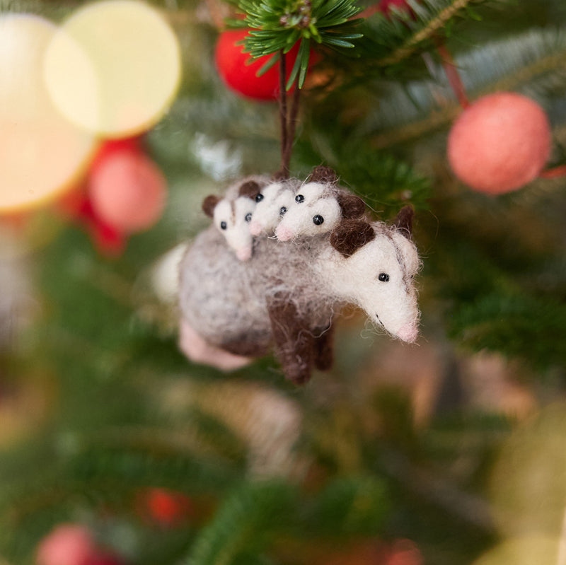 Craftspring’s Opossum Mom with Babies Ornament displayed on a Christmas tree — needle felted with three tiny babies on her back, each with adorable faces and pink tails, adding whimsical charm and festive warmth to your holiday décor — heirloom-quality ornament, ethically crafted by artisans using sustainable wool.