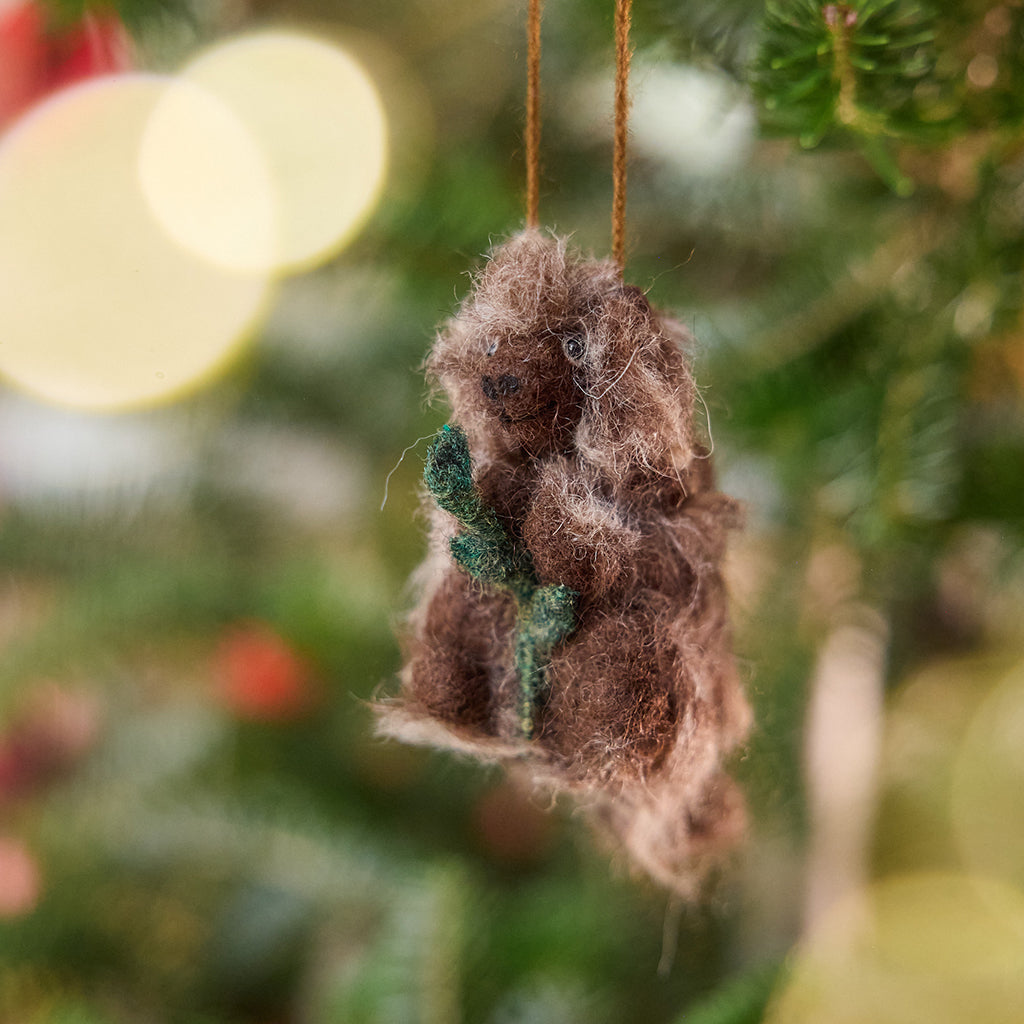 Handmade felt Porcupine ornament from Craftspring hanging on a Christmas tree, with fuzzy quills, leafy branch, and sweet details — ethically crafted by artisans using sustainable wool for heirloom-quality holiday decorating.