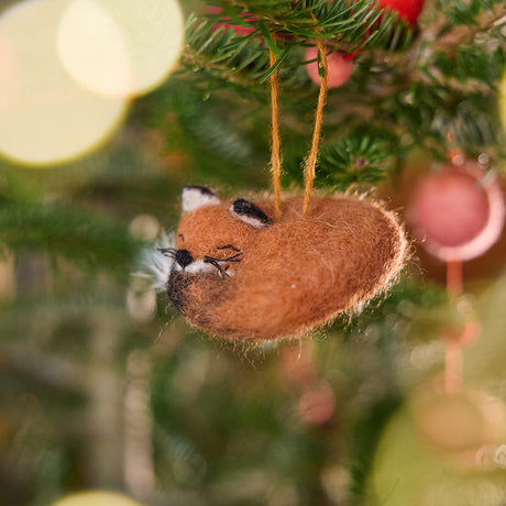 Craftspring’s Sleepy Fox Ornament displayed on a Christmas tree — needle felted with a curled-up body, cute face, fluffy tail, and whiskers, bringing festive warmth and woodland charm to your holiday traditions — heirloom-quality decor, ethically crafted by artisans using sustainable wool.