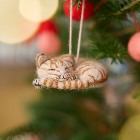 Craftspring’s Sleepy Orange Cat Ornament displayed on a Christmas tree—needle-felted with stripes, whiskers, and a cute face, adding cozy holiday warmth and gifting charm, ethically crafted by artisans using sustainable wool.