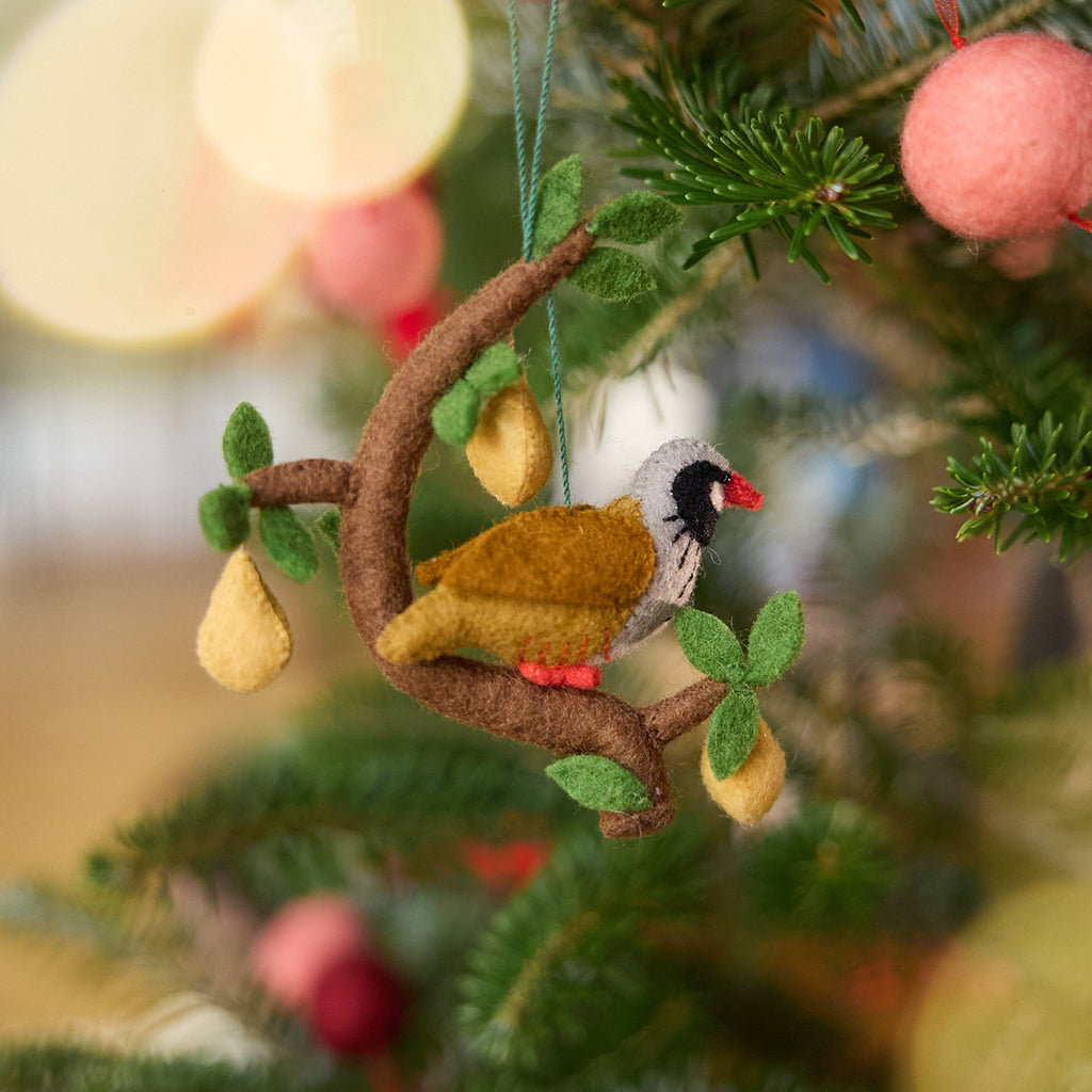 Craftspring’s Partridge in a Pear Tree Ornament displayed on a Christmas tree — a festive heirloom piece with a partridge perched in a tree and three dangling pears, perfect for Christmas gifting, ethically crafted by artisans using sustainable wool.