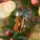 Craftspring’s Cello Ornament displayed on a Christmas tree — handmade felt heirloom with a bow, holly, and beaded and embroidered details, ethically crafted by artisans using sustainable wool, perfect for holiday gifting.