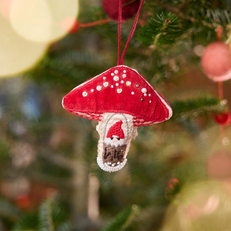 Craftspring’s Mushroom Beaded ornament — featuring a gnome peeking out of a door, with intricate beaded and embroidered details on satin and velvet, displayed on a Christmas tree for a festive woodland holiday scene, ethically crafted by artisans.