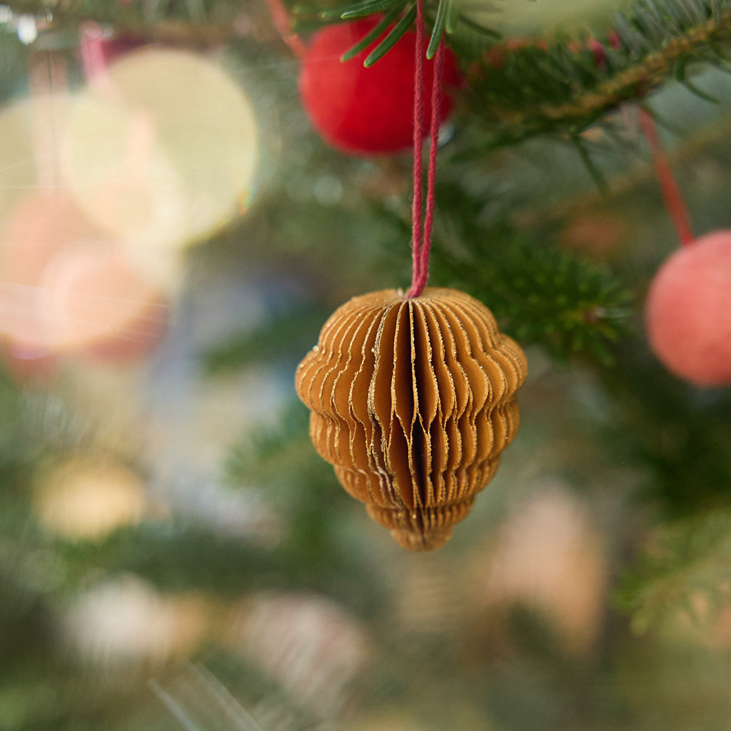 Craftspring’s pinecone honeycomb paper mini ornament with gold sparkly edges displayed on a Christmas tree — handmade by artisans from recycled cotton waste.