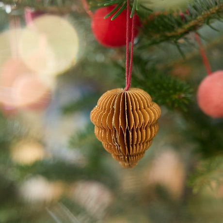 Craftspring’s pinecone honeycomb paper mini ornament with gold sparkly edges displayed on a Christmas tree — handmade by artisans from recycled cotton waste.