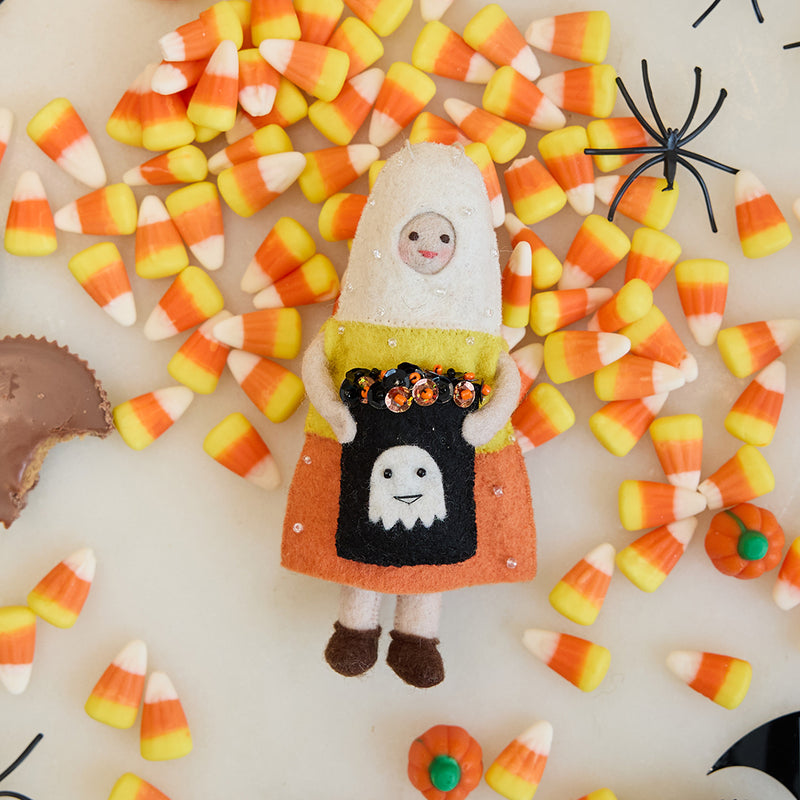 Candy Corn Trick-or-Treater Ornament displayed among bright candy corn pieces, showing its beaded candy corn costume and embroidered candy bag in a playful Halloween scene.