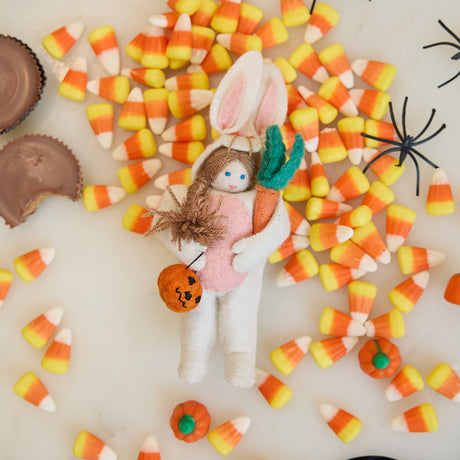 Craftspring’s handmade felt Easter Bunny Trick-Or-Treater ornament — featuring a girl in an Easter Bunny costume holding a pumpkin basket, displayed among candy corn for a festive Halloween scene, perfect for Halloween, autumn, and holiday gifting, ethically crafted by artisans using sustainable wool.