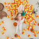 Craftspring’s handmade felt Easter Bunny Trick-Or-Treater ornament — featuring a girl in an Easter Bunny costume holding a pumpkin basket, displayed among candy corn for a festive Halloween scene, perfect for Halloween, autumn, and holiday gifting, ethically crafted by artisans using sustainable wool.