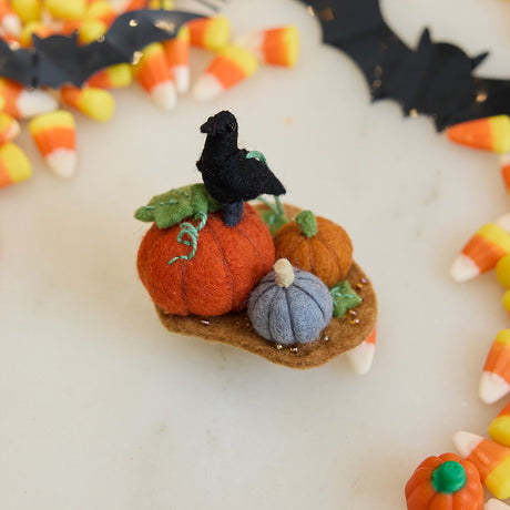 Craftspring’s handmade felt Pumpkin Patch ornament — featuring pumpkins and a crow, with beaded and embroidered details, displayed among Halloween candy for a festive autumn scene, perfect for Halloween, Thanksgiving, and holiday gifting, ethically crafted by artisans using sustainable wool.