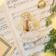 Vintage-Style Angel Playing Trumpet Ornament displayed on sheet music — handmade felt holiday ornament with intricate beaded and embroidered details, showing an angel playing a trumpet, ethically crafted by artisans using sustainable wool.