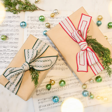 Craftspring’s Embroidered Linen Ribbons tied around Christmas presents — one with red embroidery, one with green embroidery — adding a festive, sustainable touch to holiday gifting, ethically crafted by artisans.