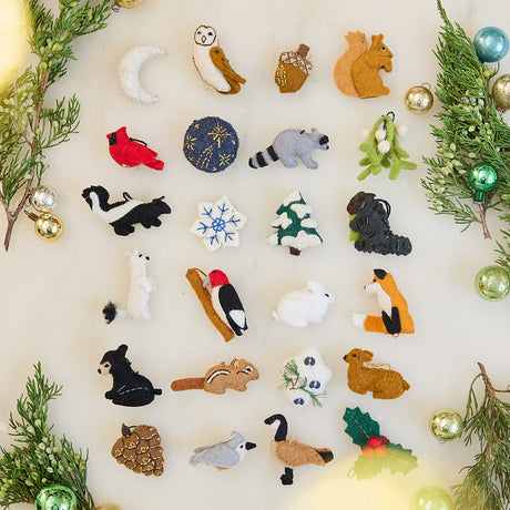 Craftspring’s set of 24 mini woodland ornaments from the Woodland Minis Advent Calendar — featuring intricate embroidered and beaded details of animals, plants, the moon, and more, perfect for adding festive woodland charm to holiday decorating or gifting, ethically crafted by artisans using sustainable wool.