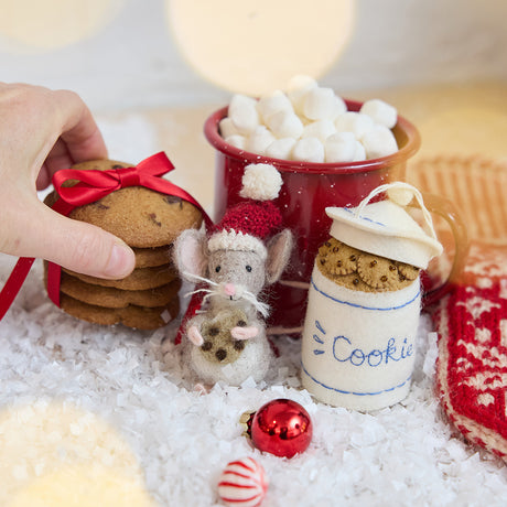 Craftspring’s Santa Mouse with Cookie Ornament and Cookie Jar Ornament — needle felted mouse with a cute face and whiskers wearing a knitted Santa hat, holding a cookie, alongside felt cookie jar ornament filled with festive treats — displayed on snow with cookies and hot cocoa, evoking cozy holiday charm, playful Christmas spirit, and heirloom-quality gifting, ethically crafted by artisans using sustainable wool.