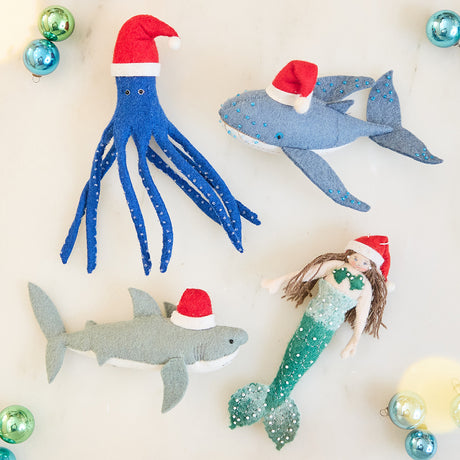Craftspring’s Christmas Ocean Ornaments Bundle — includes Christmas Mermaid Ornament, Happy Santa Humpback Ornament, Jolly Santa Shark Ornament, and Blue Santapus Ornament — displayed together in a cozy holiday setting, highlighting their playful designs with Santa hats and intricate embroidered and beaded details, evoking festive warmth and heirloom-quality Christmas gifting, ethically crafted by artisans using sustainable wool.