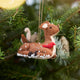 Craftspring’s Sitting Deer with Friends ornament — featuring a deer with a bunny, squirrel, and bird nestled around it, with intricate beaded snow and embroidered details — displayed on a Christmas tree for a festive woodland holiday scene, ethically crafted by artisans using sustainable wool.