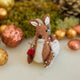 Handmade felt Sitting Deer with Friends Ornament from Craftspring, featuring a deer, rabbit, squirrel, and bird surrounded by beaded snow—displayed in a festive woodland holiday scene with golden walnuts and moss, perfect for Christmas gifting, ethically crafted by artisans using sustainable wool.
