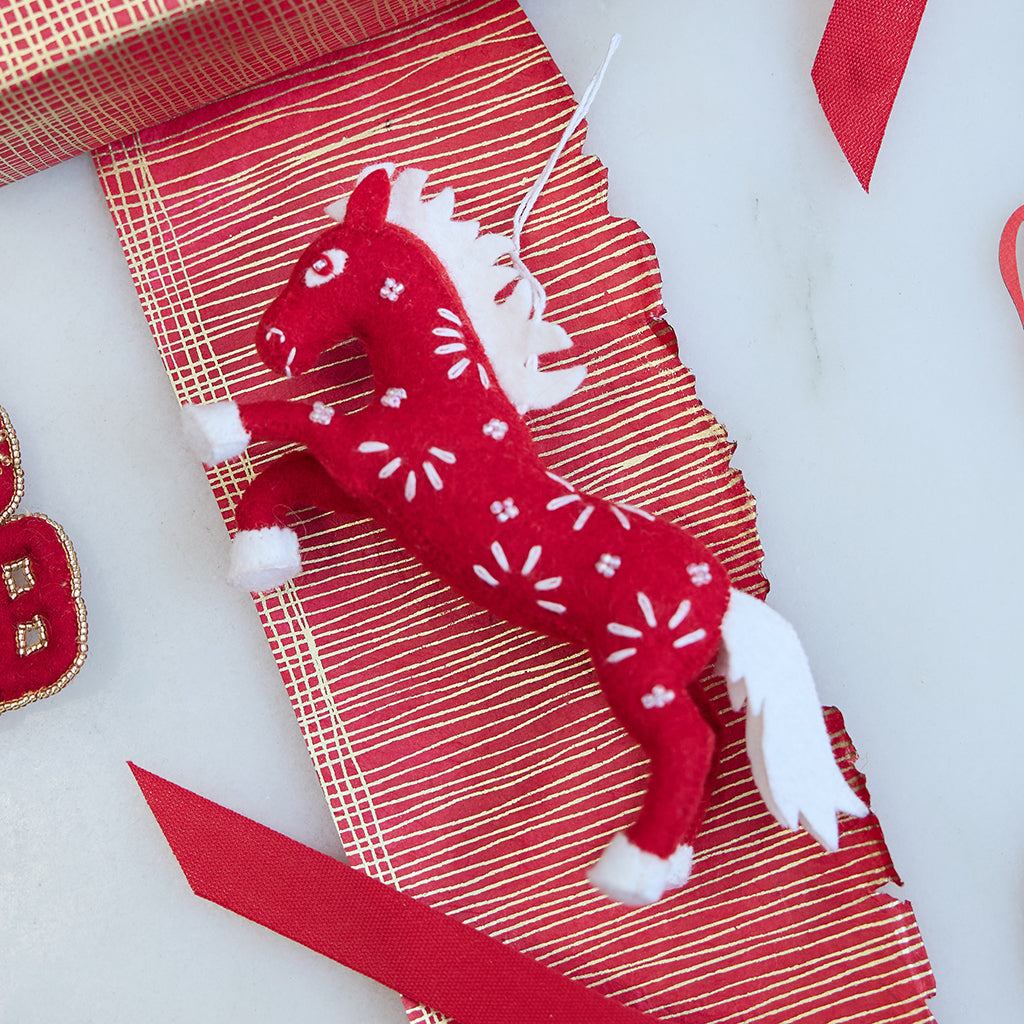 Chinese Red Horse Ornament arranged in a vibrant Lunar New Year scene, showing its intricate felt craftsmanship and celebratory embroidered accents.