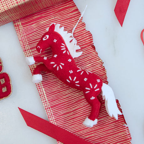 Chinese Red Horse Ornament arranged in a vibrant Lunar New Year scene, showing its intricate felt craftsmanship and celebratory embroidered accents.
