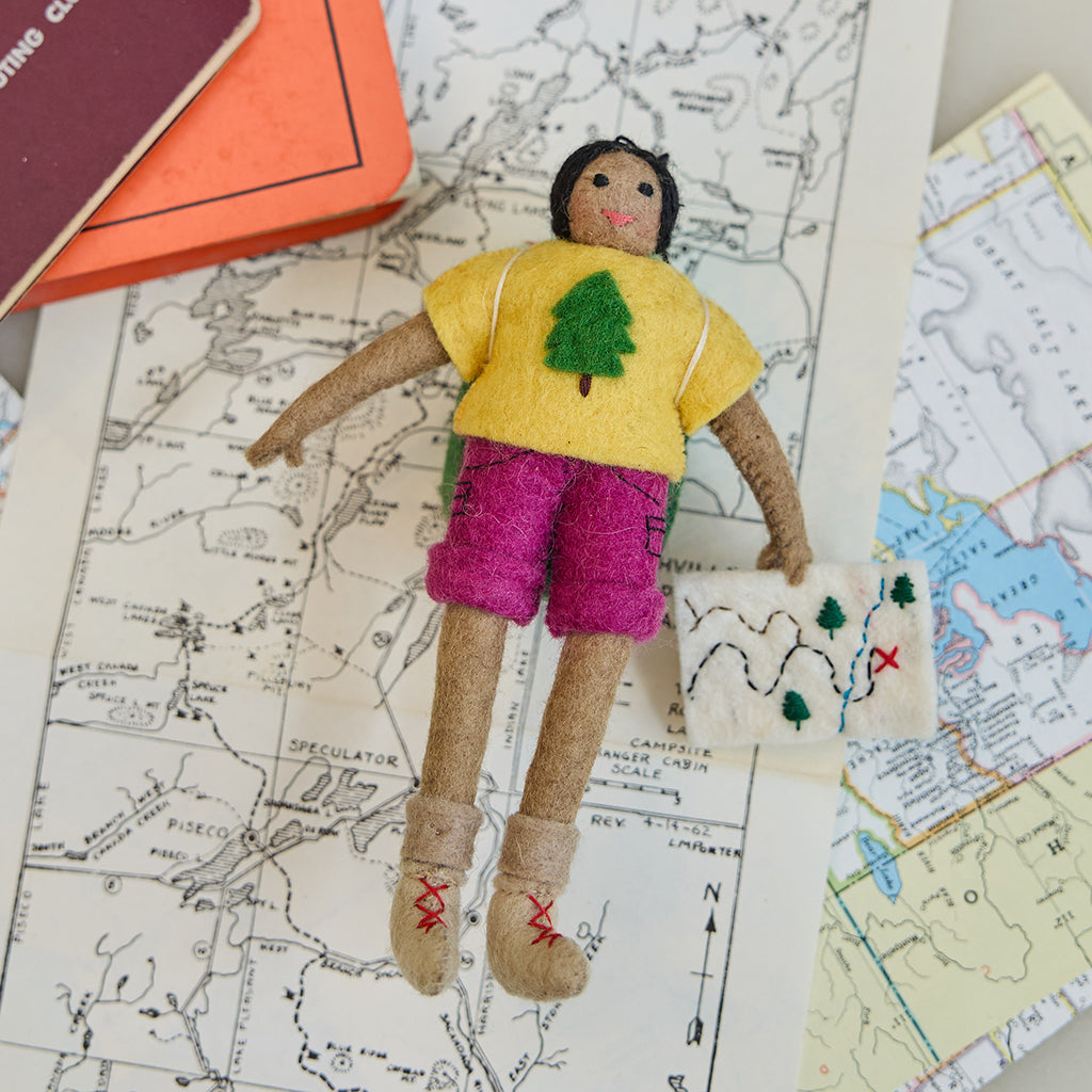 Handmade felt On the Trail Backpacker Ornament – Brown from Craftspring, backpacker girl holding a map—displayed on a trail map, evoking outdoor adventure and holiday gifting, heirloom-quality Christmas decor, ethically handcrafted by artisans.