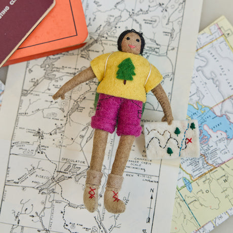 Handmade felt On the Trail Backpacker Ornament – Brown from Craftspring, backpacker girl holding a map—displayed on a trail map, evoking outdoor adventure and holiday gifting, heirloom-quality Christmas decor, ethically handcrafted by artisans.