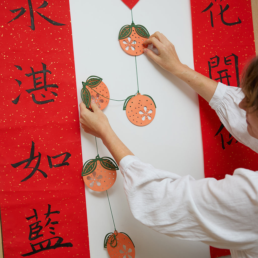 Paper Clementine Garland — set of 2 handmade garlands, each with 5 clementines featuring leaves and intricate cutout details, ethically handmade by artisans from recycled cotton waste — festive Christmas, holiday, and Lunar New Year decor, perfect for joyful gifting.