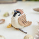 Celebrate the quiet beauty of everyday birds with our Sparrow Ornament. Small yet full of personality, this beloved garden bird is lovingly hand-felted from natural wool and perched on a delicate felt branch.