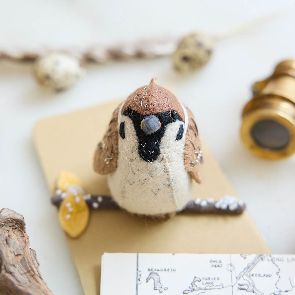 Celebrate the quiet beauty of everyday birds with our Sparrow Ornament. Small yet full of personality, this beloved garden bird is lovingly hand-felted from natural wool and perched on a delicate felt branch.