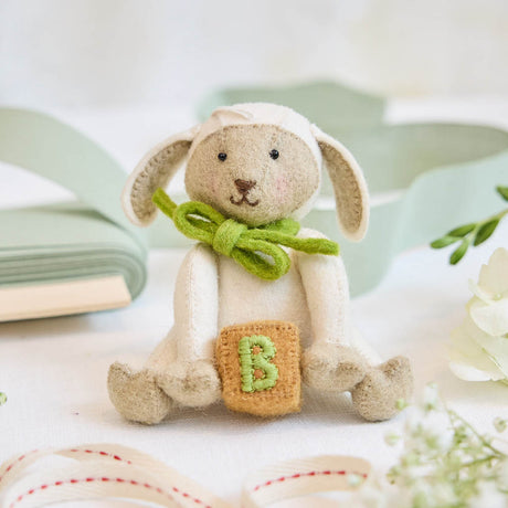 Soft, sweet, and timeless, this charming lamb ornament is carefully handcrafted from natural wool felt. With its floppy ears, gentle expression, and bright green bow, it holds a tiny embroidered “B” block—symbolizing baby’s earliest milestones.&nbsp;