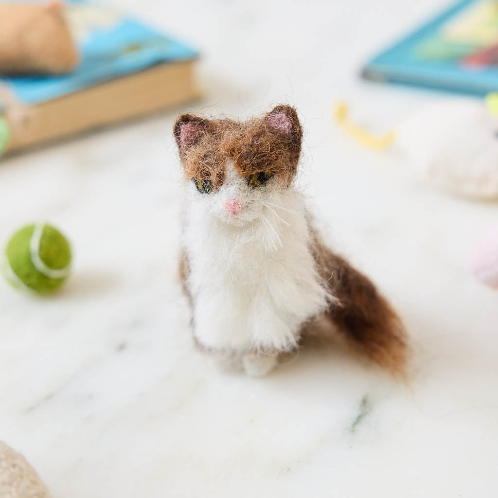Celebrate the unique beauty of feline companions with our felt Calico Cat Ornament. Carefully handcrafted by skilled artisans, this elegant ornament features the signature patchwork of warm browns, soft whites, and golden tones that make calico cats so beloved.