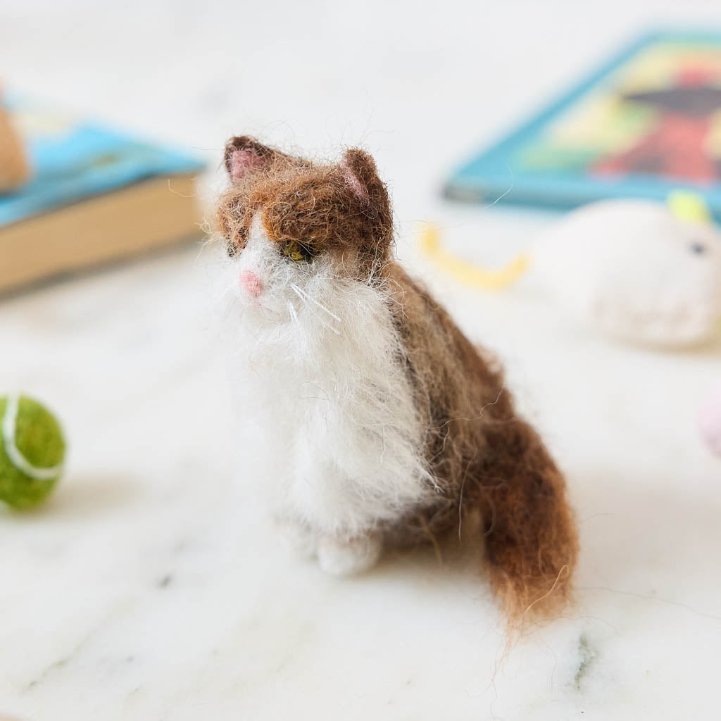 Celebrate the unique beauty of feline companions with our felt Calico Cat Ornament. Carefully handcrafted by skilled artisans, this elegant ornament features the signature patchwork of warm browns, soft whites, and golden tones that make calico cats so beloved.
